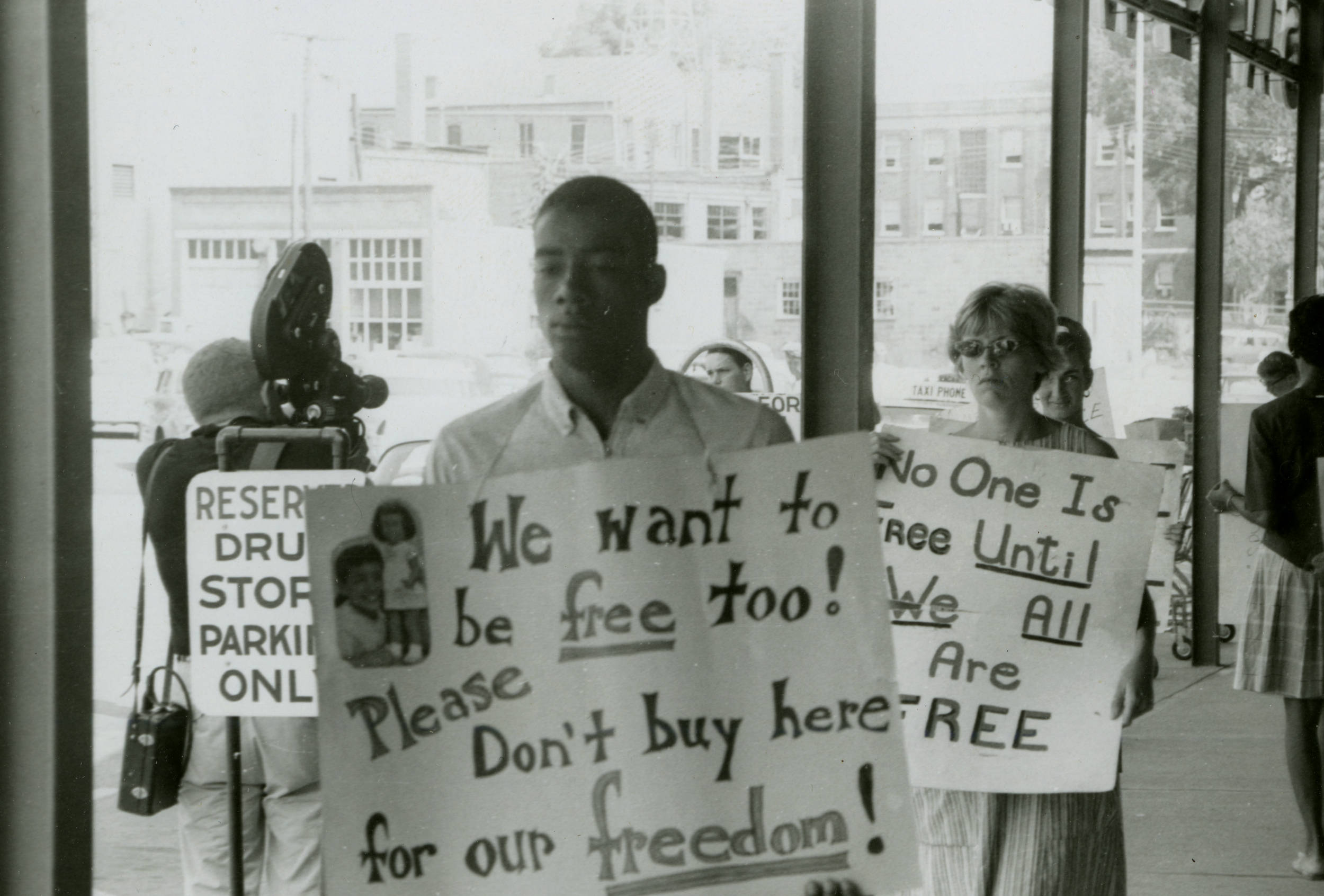 A group of protestors, both Black and White, holding picket signs and demonstrating